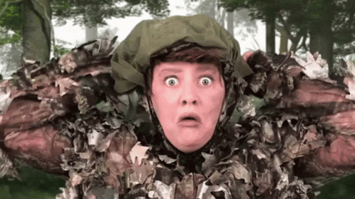 A Woman In A Camouflage Outfit Has A Surprised Look On Her Face . GIF