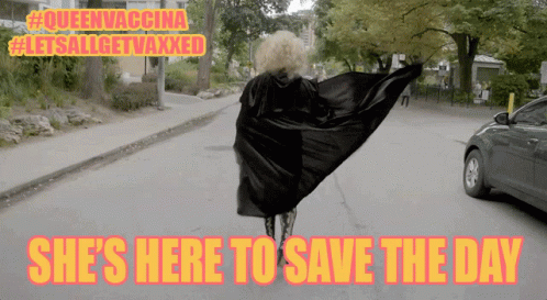A Woman In A Cape Is Walking Down A Street With The Words She 'S Here To Save The Day GIF