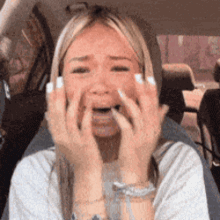 A Woman In A Car Is Covering Her Face With Her Hands GIF