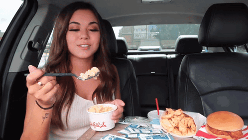 A Woman In A Car Is Eating Macaroni And Cheese From A Cup That Says Chick-Fil-A GIF