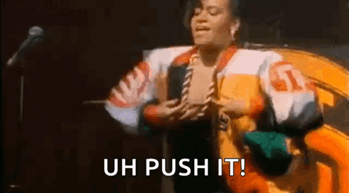 A Woman In A Colorful Jacket Is Singing Into A Microphone And Saying `` Uh Push It ! '' GIF