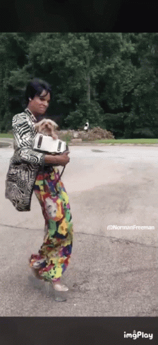 A Woman In A Colorful Outfit Is Holding A Dog In Her Arms .. GIF