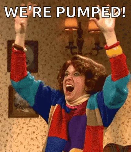 A Woman In A Colorful Sweater Is Raising Her Arms In The Air With The Words We 'Re Pumped Written Above Her GIF