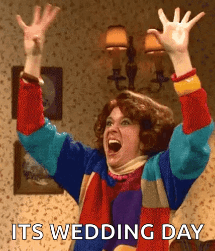 A Woman In A Colorful Sweater With Her Arms In The Air And The Words Its Wedding Day Below Her GIF