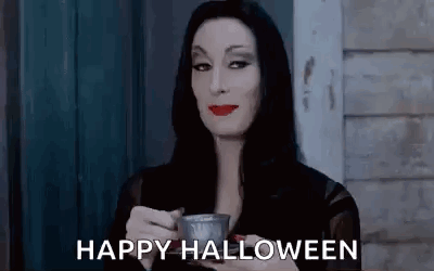 A Woman In A Costume Is Holding A Cup Of Coffee And Saying `` Happy Halloween '' . GIF