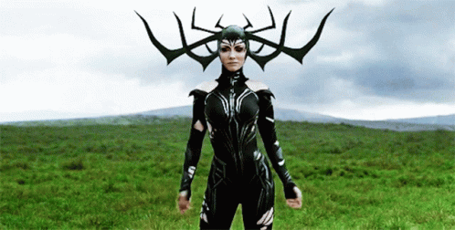 A Woman In A Costume With Horns On Her Head Is Standing In A Field . GIF