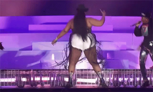 A Woman In A Cowboy Hat Is Dancing On A Stage While Another Woman Sings Into A Microphone GIF