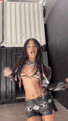 A Woman In A Crop Top And Leather Shorts Is Dancing . GIF