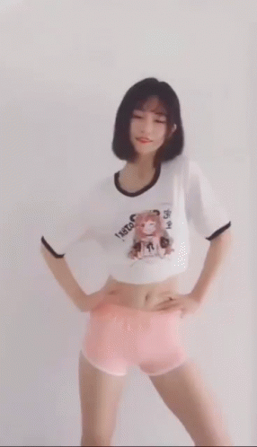 A Woman In A Crop Top And Pink Shorts Is Dancing . GIF
