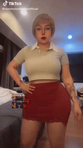 A Woman In A Crop Top And Red Skirt Is Standing With Her Hands On Her Hips . GIF