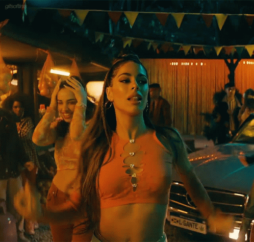 a woman in a crop top is dancing in front of a car with a license plate that says ante on it