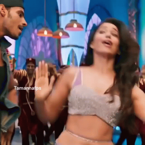 A Woman In A Crop Top Is Dancing With A Man In A Hat . GIF