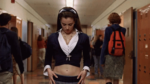 A Woman In A Crop Top Stands In A Hallway With Lockers GIF