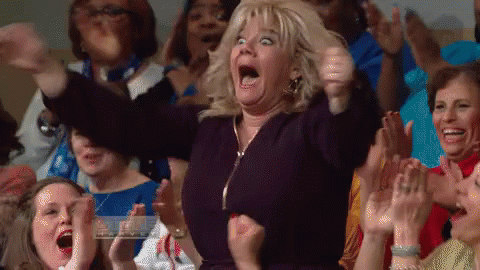 A Woman In A Crowd Of People Is Making A Funny Face . GIF