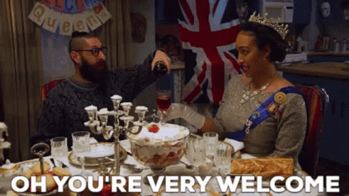 a woman in a crown is sitting at a table with a man pouring wine