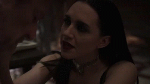 A Woman In A Dark Room Is Looking At Another Woman . GIF