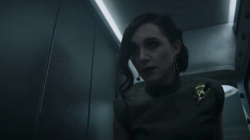 A Woman In A Dark Room With A Badge That Says U.s. Army On It GIF