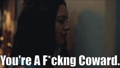 A Woman In A Dark Room With The Words You 'Re A F * Cking Coward GIF