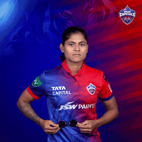 A Woman In A Delhi Capitals Shirt Holds Sunglasses GIF
