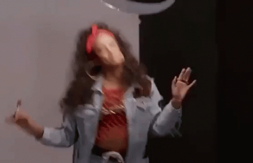 A Woman In A Denim Jacket Is Dancing In A Room . GIF