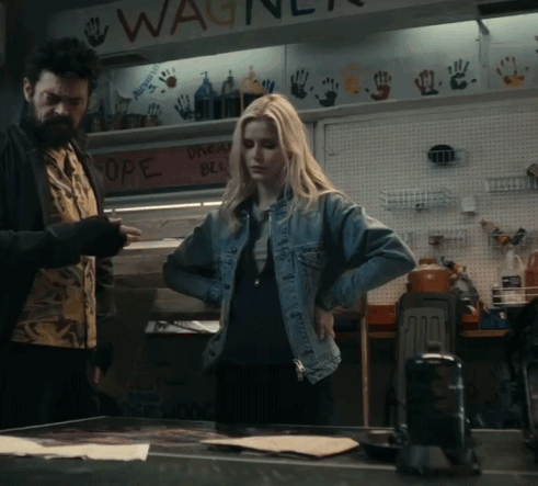 A Woman In A Denim Jacket Is Standing In Front Of A Sign That Says Wagner GIF