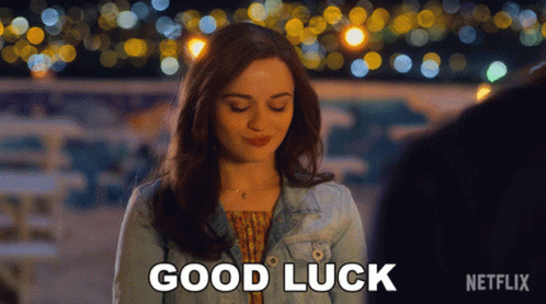 A Woman In A Denim Jacket Says Good Luck In Front Of A Blurry Background GIF