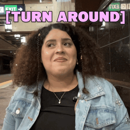 A Woman In A Denim Jacket With The Words Turn Around Behind Her GIF