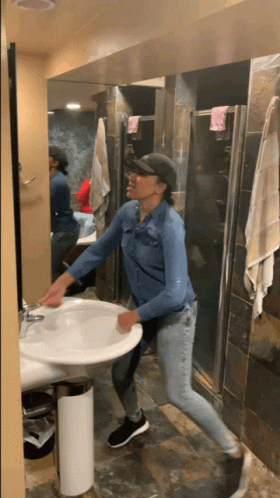 A Woman In A Denim Shirt Is Cleaning A Sink GIF
