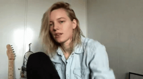 A Woman In A Denim Shirt Is Sitting In Front Of A Microphone In A Room . GIF