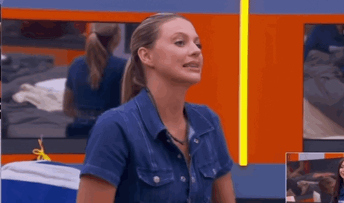 A Woman In A Denim Shirt Is Sitting In Front Of A Mirror GIF