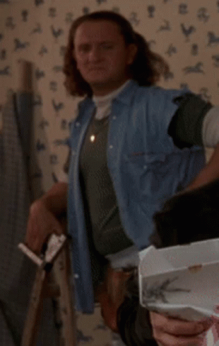 A Woman In A Denim Vest Is Standing In Front Of A Wall With Chickens On It GIF
