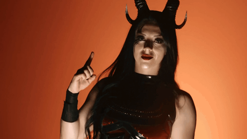 A Woman In A Devil Costume With Horns Pointing Up GIF