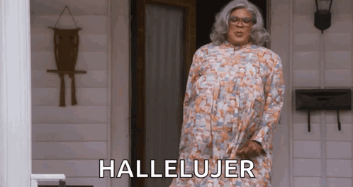 A Woman In A Dress Is Standing In Front Of A Door With The Word Hallelujar Written On It . GIF