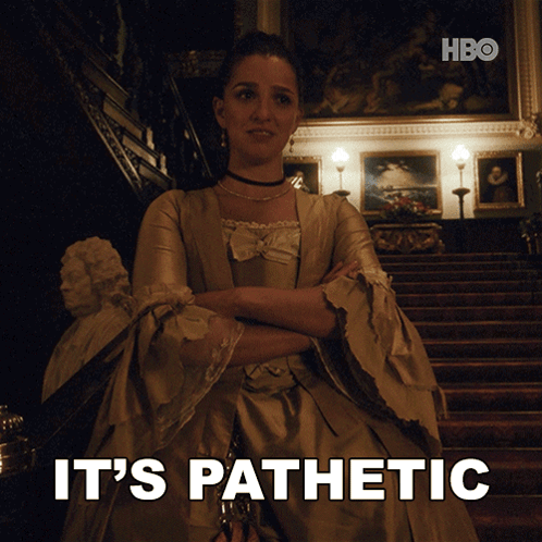 A Woman In A Dress Is Standing In Front Of A Staircase With The Words " It 'S Pathetic " Behind Her GIF