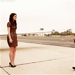 A Woman In A Dress Is Standing Next To A Man On A Runway GIF