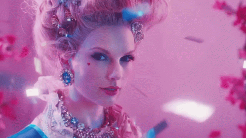 A Woman In A Fancy Dress Costume With A Heart On Her Cheek Looks At The Camera GIF