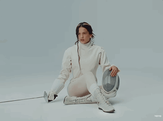 A Woman In A Fencing Outfit Is Kneeling Down Holding A Sword And A Helmet GIF
