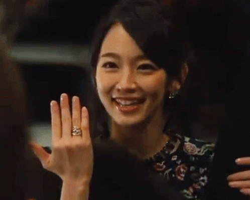 A Woman In A Floral Dress Is Laughing With Her Mouth Open . GIF