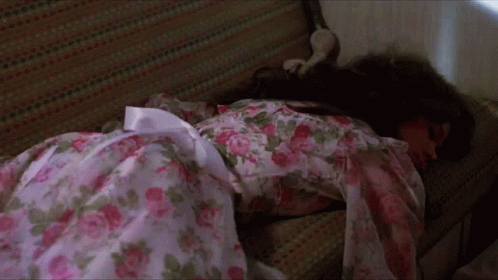 A Woman In A Floral Dress Is Laying On A Couch GIF