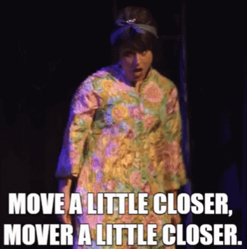 A Woman In A Floral Dress Is Saying Move A Little Closer , Mover A Little Closer . GIF