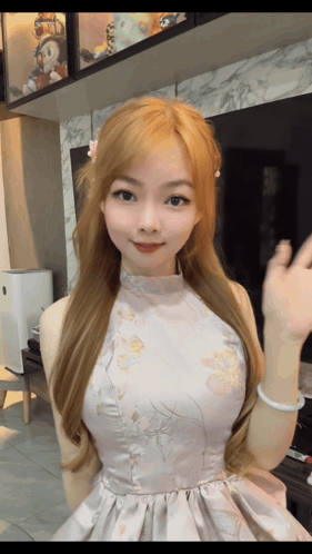 A Woman In A Floral Dress Is Waving Her Hand GIF