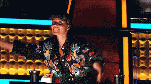 A Woman In A Floral Jacket Is Sitting In A Chair With Her Arms Outstretched .. GIF