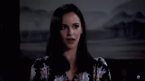 A Woman In A Floral Shirt Is Standing In Front Of A Large H . GIF