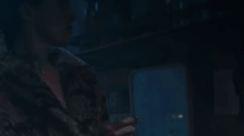 A Woman In A Fur Coat Is Looking Up At Something GIF