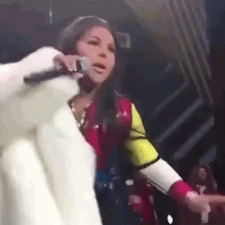 a woman in a fur coat is singing into a microphone