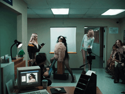 A Woman In A Fur Coat Is Standing In Front Of A Computer Screen GIF