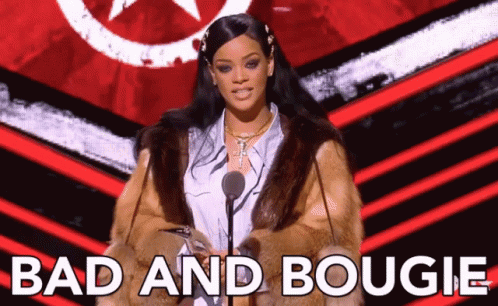 A Woman In A Fur Coat Is Standing In Front Of A Microphone And The Words Bad And Bougie Are Behind Her GIF