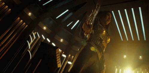 a woman in a futuristic outfit is holding a sword in a dark room