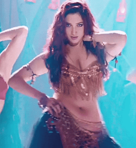 A Woman In A Gold Top Is Dancing On A Stage GIF