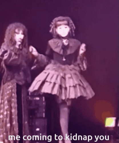 A Woman In A Gothic Dress Is Standing Next To Another Woman In A Purple Dress . GIF